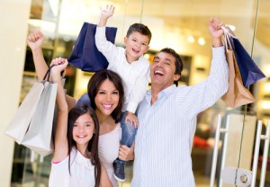 Excited shopping family with arms up holding bags